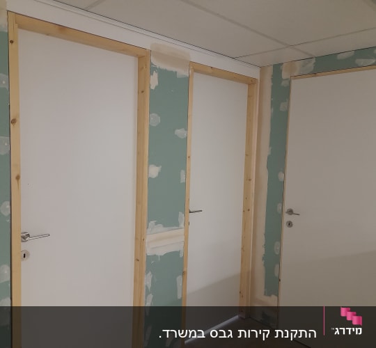 קירות גבס עם דלתות לבנות ומסגרות עץ
